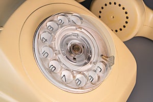 Old yellow antique rotary telephone with removed handset receiver on grey background. Vintage landline home phone with