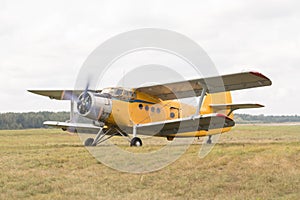 Old yellow biplane with switched on motor stay on grass field