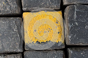 Old yellow and black granite road cubes or cobbles as background or wallpaper. Vertical image.