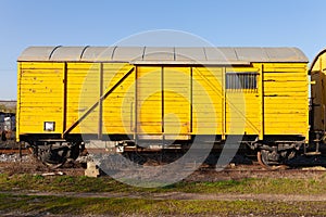 Old yellow cargo train wagon, grungy and weathered on the abandoned train tracks