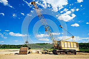 Old yellow excavator under blue sky