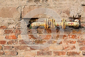 Old yellow gas pipe in a brick wall. Strange design