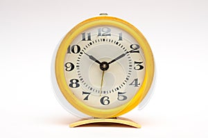 Old yellow mechanical alarm clock on white background