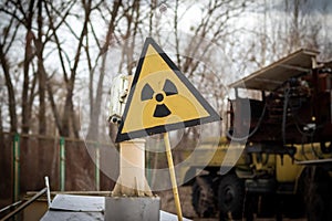 Old yellow radiation sign against a blurred background of equipment that participated in the liquidation of the accident