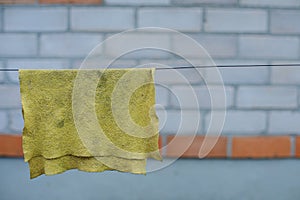 An old yellow rag for cleaning dries up in the street. A rag hangs on a rope