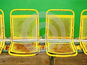 Old yellow rusty metal seats on outdoor stadium. Players bench chairs