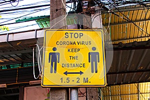 Old Yellow sign inform Social distance due to COVID-19 in famous Chatuchak Market in Thailand.