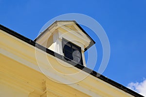 old yellow stucco roof dormer with small wood window. sloped clay tile roof . metal flashing trimmed edges