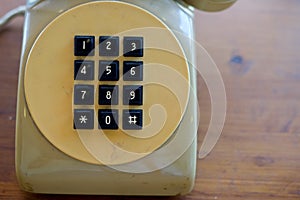 Old yellow telephone with black key pad