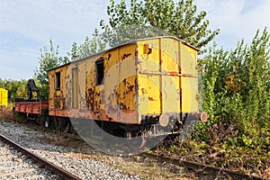 Old yellow train with big holes, rusty and abandoned in the field