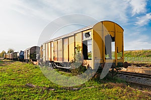 Old yellow train with big holes, rusty and abandoned on the old tracks in the field