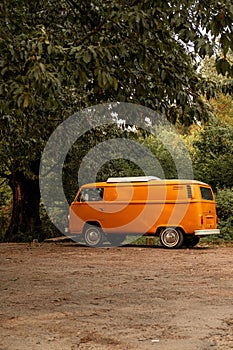 an old yellow van is parked on the dirt path near trees photo