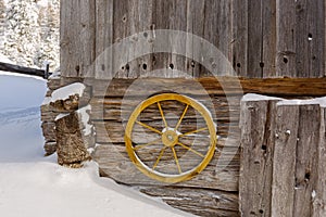 Old yellow wagon wheel hanging on wall to decorate rustic wooden
