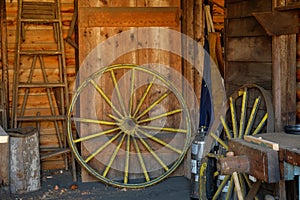 Old yellow wagon wheel waiting for restoration in an old barn