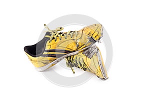 Old yellow worn out futsal sports shoes on white background soccer sportware object isolated