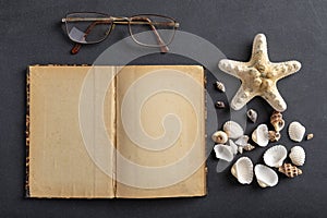 Old yellowed notebook, glasses and seashells. A place to save your holiday memories