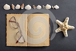 Old yellowed notebook, glasses and seashells. A place to save your holiday memories