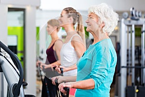 Old and young people on vibrating plates in gym