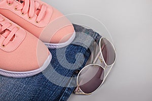 Olded jeans, pink sneakers and sunglasses. flat layout with folded jeans, sneakers, glasses. Casual fashion clothes. Autumn