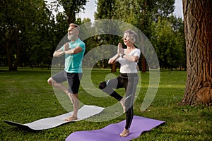 Older active couple doing yoga exercise outdoors at city park