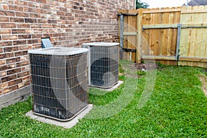 Older air conditioner units next to brick home with copy space