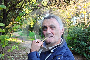 Older Armenian Man smoking a pipe in the park Athens Greece 1-3-2018