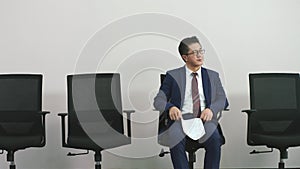 Older asian corporate executive waiting in chair for job interview