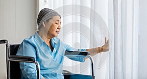 Older Asian woman patient covered the head with clothes effect from chemo treatment in cancer cure process lonely sitting on