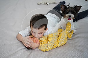 older brother with dog kisses newborn sister. birth of second child in family.