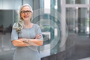Older business woman CEO standing and smiling confident, successful, at office building with copy space