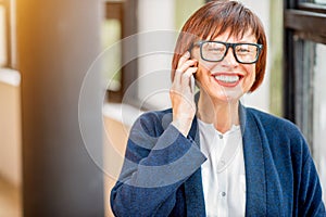 Older businesswoman talking phone indoors