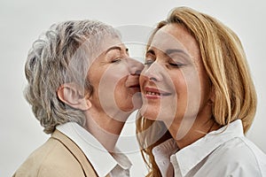 Older Caucasian mother kiss adult daughter