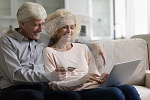 Older couple buying on internet using laptop and debit card