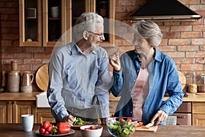 Older couple cooking together healthy food in modern kitchen