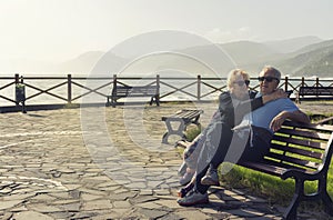 Older couple enjoying outdoors, resting in the park beside the ocean