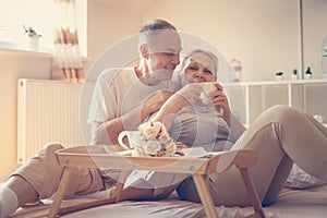 Older couple having breakfast on bed.