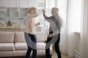 Older couple holding hands dancing together in modern living room