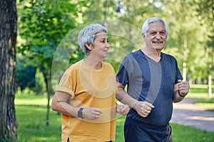 Older couple jogging in the summer park