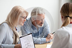 Older couple reading contract at meeting with real estate agent