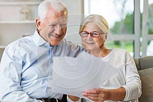 Older couple reading papers together on sofa