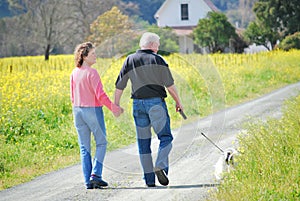 Older couple walking their dog on a country road