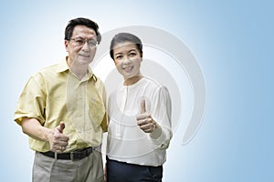 Older couples raise their thumbs to show confidence in their health, isolated on blue background with clipping path