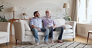 Older father his adult son fist bumping seated on sofa