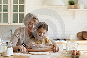 Older female nanny rolling dough cooking bakery with little child