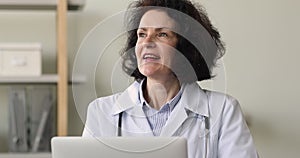 Older general practitioner sit at workplace working on laptop