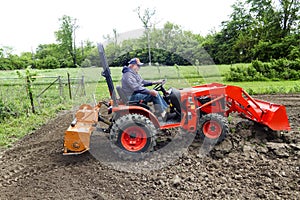 Older Gentleman Tilling His Garden With A Compact 4x4 Tractor