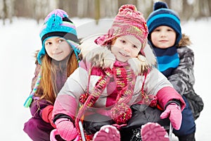 Older girl and boy push sled in which younger girl sits