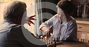 Older grandpa and little grandson play chess at home