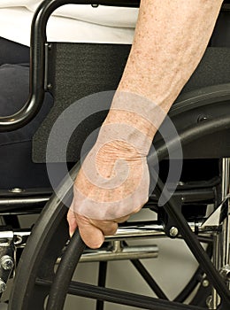 Older hand on wheel chair pushing