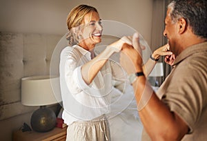 Older interracial couple dancing in a hotel bedroom together on a romantic holiday. Senior hispanic man and caucasian